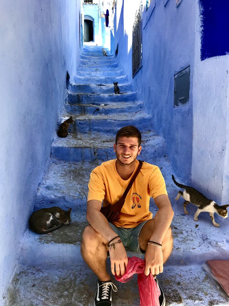 Ángel Herrera en una calle de Chefchaouen con gatos