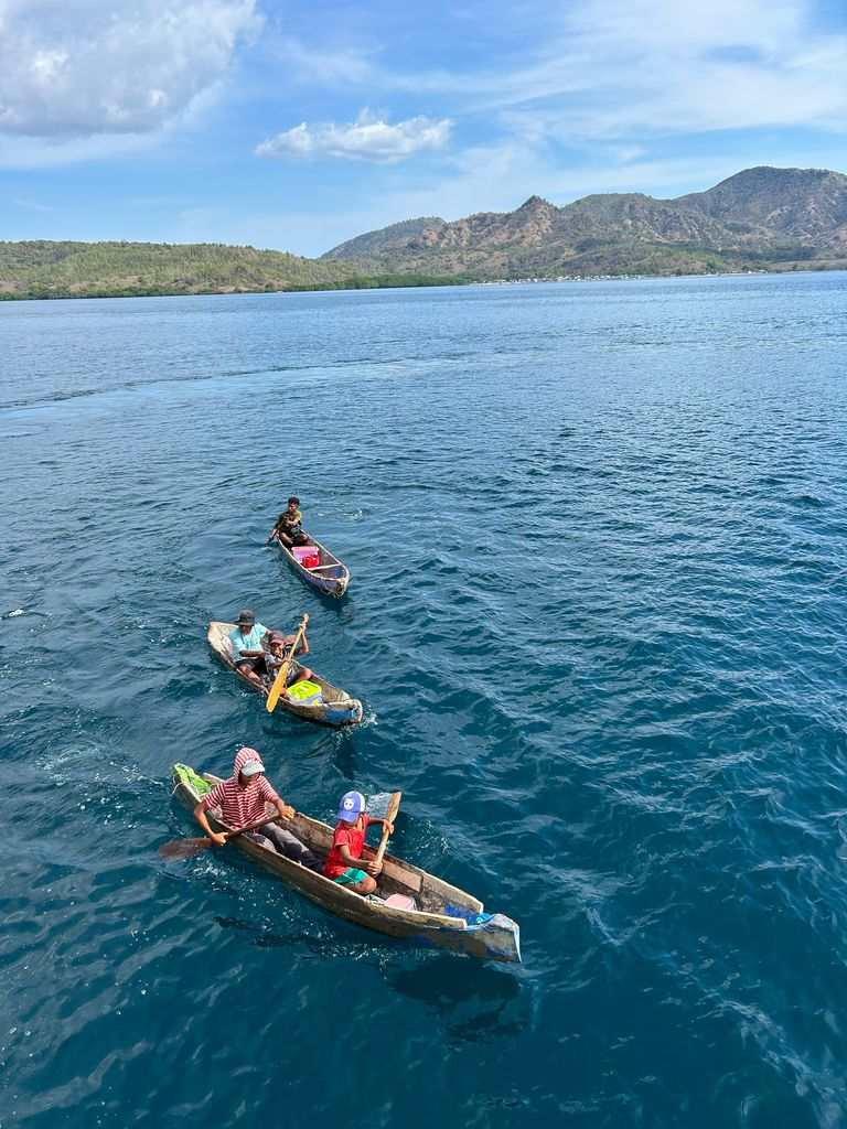 Niños en Komodo yendo en barca para vender artesanías